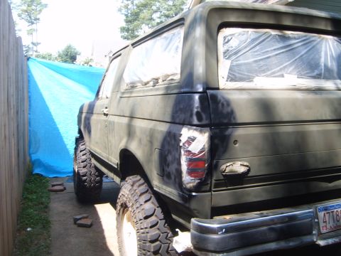 1988 Ford Bronco - The rear of a modified SUV, possibly a Ford Bronco, is shown with its windows covered in plastic sheeting.