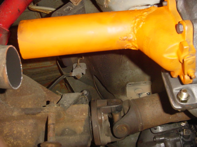 Close-up of a driveshaft connected to a differential, with an orange painted component above