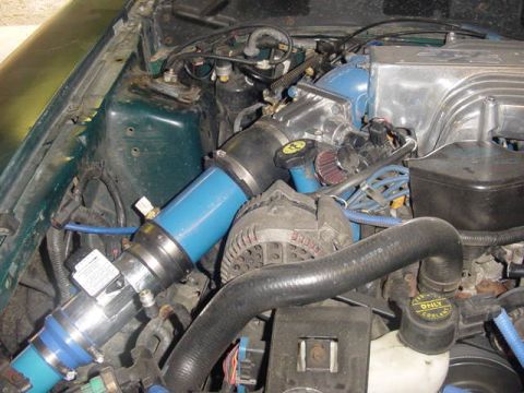 1995 Ford Mustang - Close-up of an engine bay with custom intake piping and various engine parts visible.