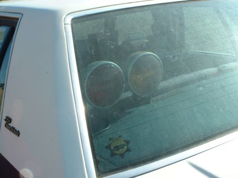 1999 Ford Crown Victoria - Interior view of a 1999 Ford Crown Victoria, two circular lights and a law enforcement sticker on the rear window.