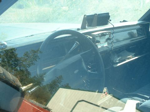 1999 Ford Crown Victoria - The interior of a police car shows a radio unit and steering wheel.