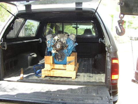 1995 Ford Bronco - An engine is secured on a wooden pallet inside the bed of a dark-colored truck.