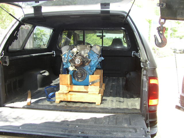 Truck bed with an engine on a wooden pallet, a hook hangs from above