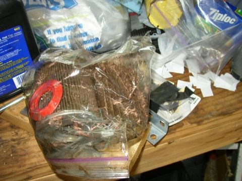 1995 Ford Bronco - A dirty oil filter is sealed in a plastic bag, alongside other automotive parts and fluids.