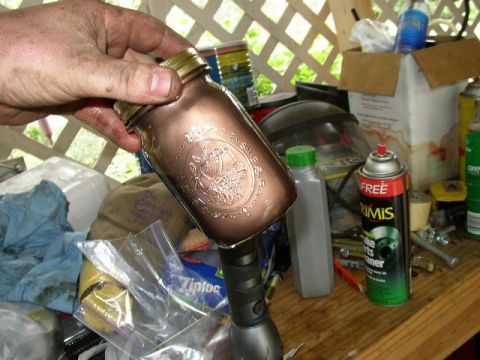1995 Ford Bronco - Hand holds a copper mason jar over a workbench cluttered with automotive supplies.