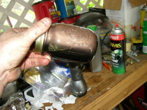 1995 Ford Bronco - A hand holds a jar filled with dark, used motor oil, with various automotive supplies visible in the background.