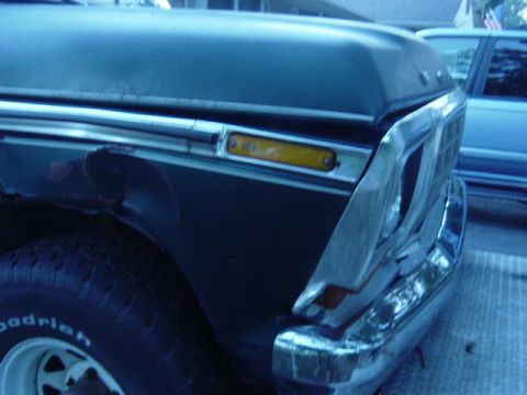 1987 Suzuki Samurai - Close-up of a truck's front fender and grille, with another vehicle in the background.