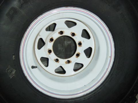 1987 Suzuki Samurai - Close-up of a white wagon wheel and tire, showing some text on the tire sidewall.