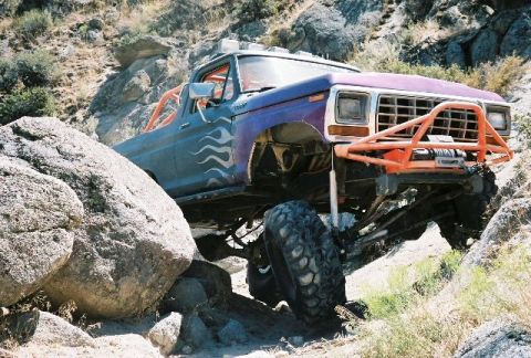 1979 Ford Bronco - This heavily modified pickup truck is shown off-roading over large rocks.