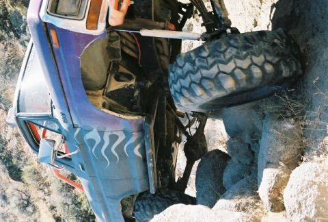 1979 Ford Bronco - This heavily modified truck appears to be struggling on a rocky trail, with one wheel elevated.