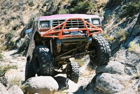 1979 Ford Bronco - Modified off-road vehicle navigates rocky terrain with large tires and a custom front bumper.