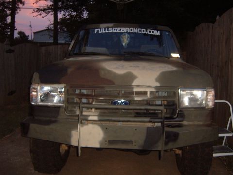 1988 Ford Bronco - This Ford Bronco is painted in camouflage and has a website banner across the top of the windshield.