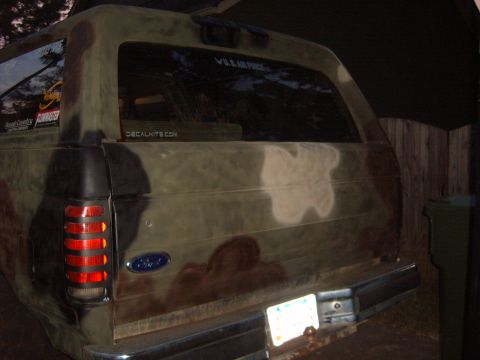 1988 Ford Bronco - Rear view of a camouflaged Ford Bronco with "V.I.L. AIR FORCE" and "DECALKITS.COM" stickers on the rear window.