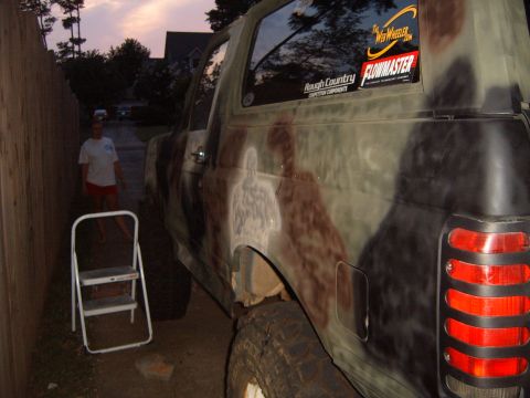1988 Ford Bronco - This camouflaged SUV is seen from the side, aftermarket stickers on the rear window.