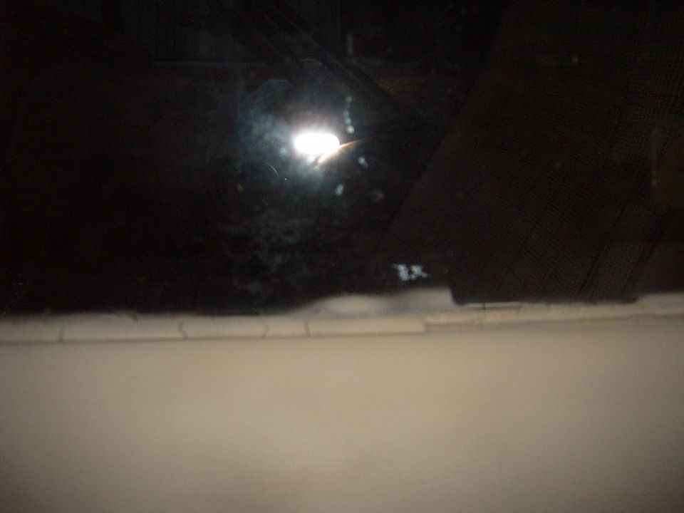 Interior view of a dark vehicle, showing a reflection on the window