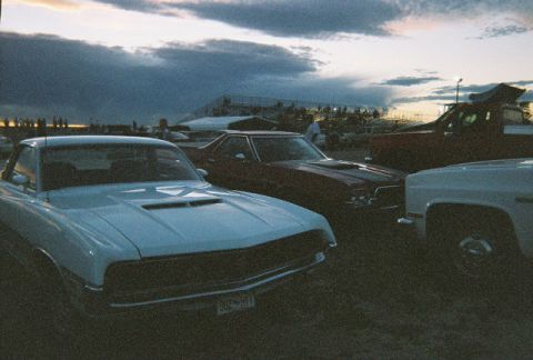 1972 Ford Ranchero - Several cars are parked at an outdoor event with a cloudy sky overhead.