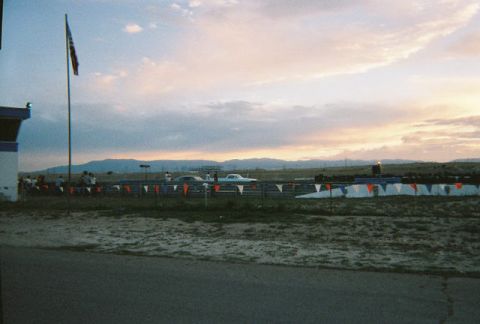 1972 Ford Ranchero - Two cars are lined up on a drag strip with a control tower and mountains in the background.