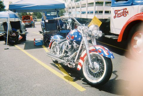 1972 Ford Ranchero - A motorcycle painted with stars and stripes is parked beside a vintage Pepsi-Cola truck at an outdoor event.