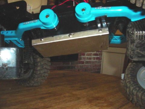 1988 Ford Bronco - Close-up of an RC crawler's suspension system and tires, with "Fabtech" visible on the blue components.