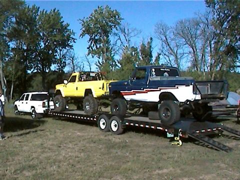 1977 Ford F-150 - A blue and white Ford F-150 pickup truck is loaded onto a trailer with a yellow pickup truck and a white SUV.