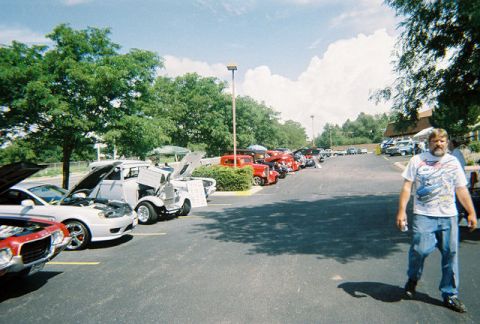 1972 Ford Ranchero - A man stands in front of a row of cars with their hoods open at an outdoor gathering.