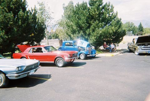 1972 Ford Ranchero - A gathering of vintage vehicles under trees, with people relaxing nearby.