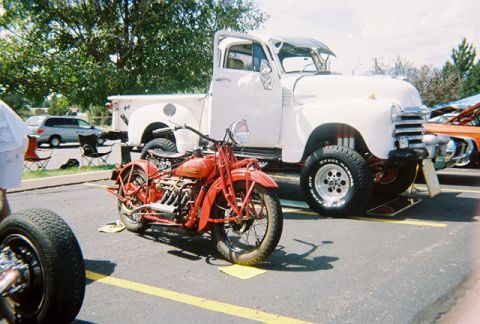 1972 Ford Ranchero - A red vintage motorcycle and a white pickup truck are displayed at an outdoor car show.