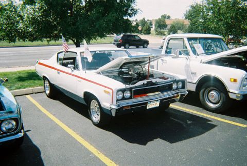 1972 Ford Ranchero - A white car with a red stripe and its hood open is parked next to a white pickup truck.