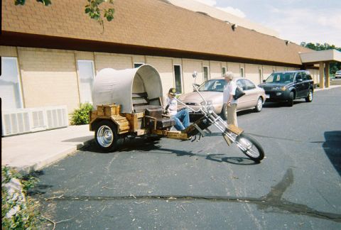 1972 Ford Ranchero - A custom motorcycle and trailer are parked next to two cars in front of a building.
