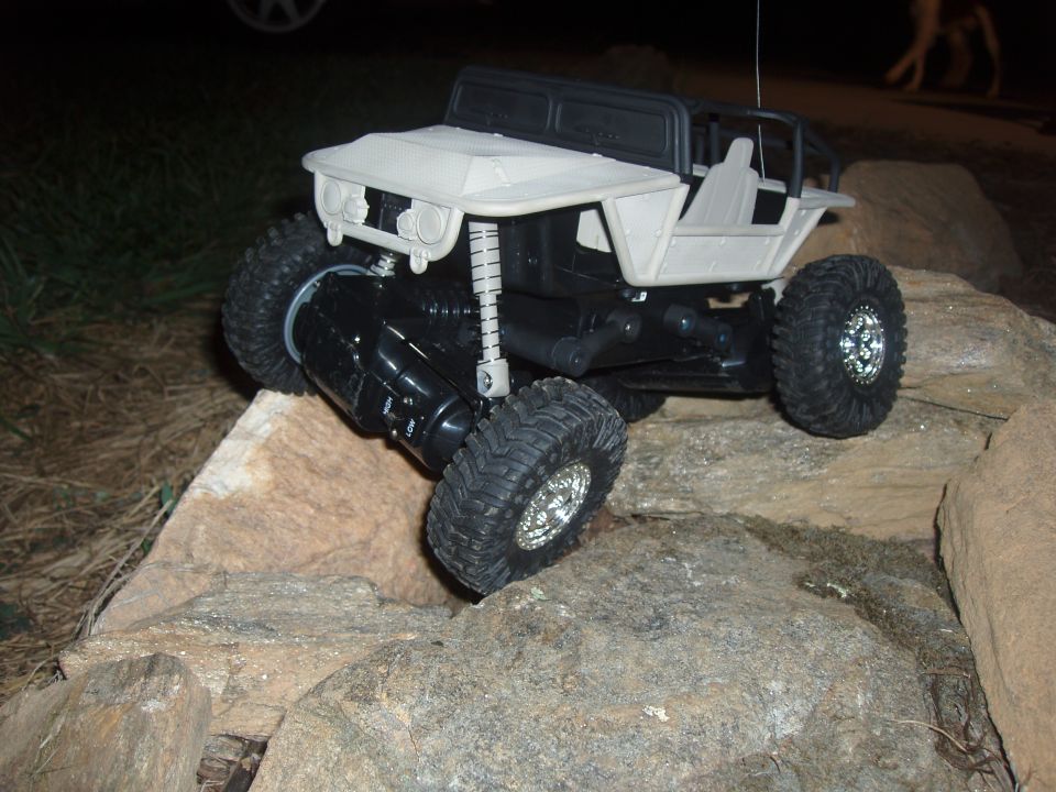 White-bodied RC rock crawler with knobby tires posed on rocks at night