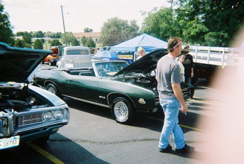 1972 Ford Ranchero - A green 1969 Pontiac GTO convertible is displayed with its hood open at an outdoor car show.