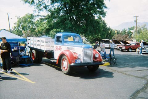 1972 Ford Ranchero - An old International truck with a flatbed is displayed at a car show, with other vehicles in the background.