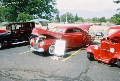 1972 Ford Ranchero - A red 1939 coupe is displayed with its hood open at a car show, alongside other vintage vehicles.