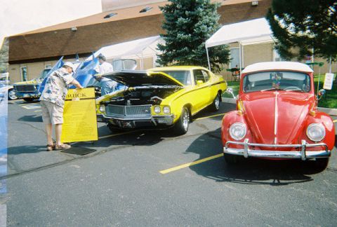 1972 Ford Ranchero - A yellow 1972 Buick Skylark is displayed with its hood open next to a red Volkswagen Beetle.