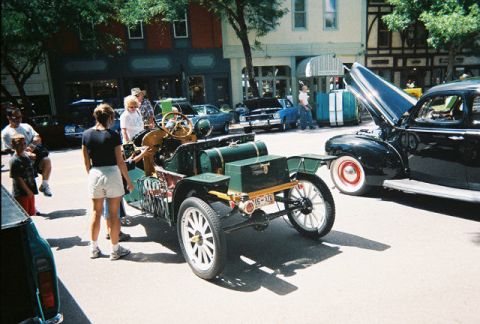 1972 Ford Ranchero - An antique green automobile is parked on a street next to other vehicles and people.