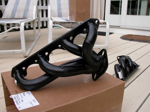 1989 Ford Bronco - Exhaust headers are shown on a deck, with chairs and a door in the background.