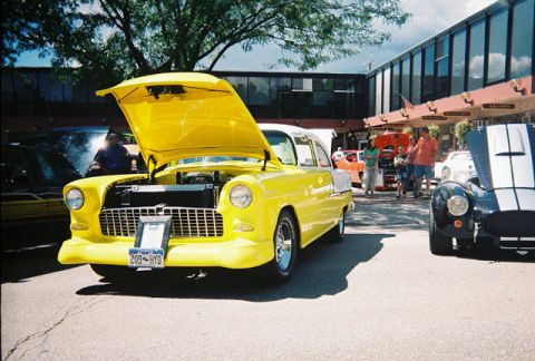 1972 Ford Ranchero - A bright yellow 1955 Chevrolet Bel Air, a classic American car, is displayed with its hood up at a car show.