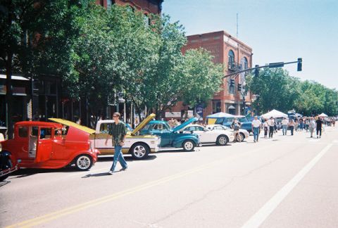 1972 Ford Ranchero - A street fair with several classic cars on display and people milling about.