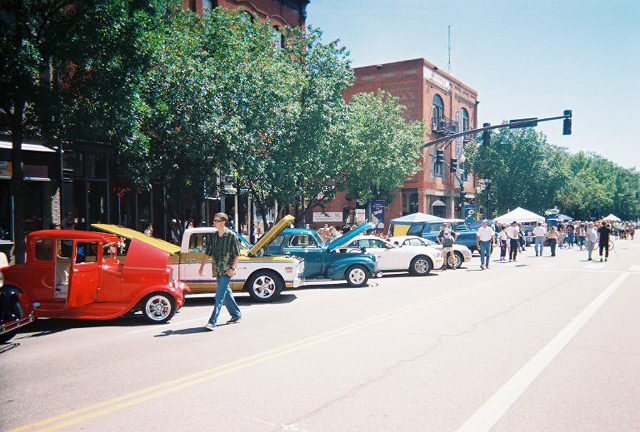 Row of classic cars including a red 1930s hot rod at a downtown street car show