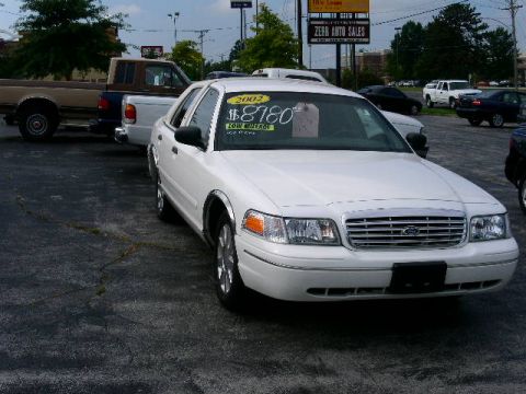 2001 Ford Crown Victoria - A white Ford Crown Victoria is parked at a car dealership with other vehicles visible in the background.