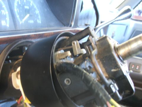 1989 Ford Bronco - Close-up of a vehicle's steering column ignition assembly, showing exposed wiring and mechanical parts.