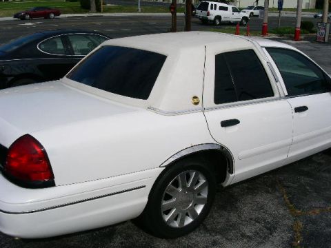 2001 Ford Crown Victoria - A white 2001 Ford Crown Victoria sedan is shown from the rear quarter angle, a vinyl roof and chrome trim.