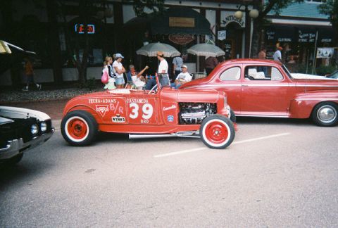 1972 Ford Ranchero - A red hot rod with racing decals and number 39 is parked on a street next to another vintage car.
