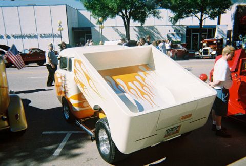 1972 Ford Ranchero - A custom pickup truck with flame graphics is displayed at a car show, with other vehicles visible in the background.