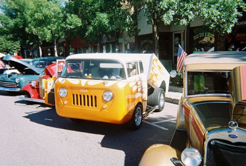 1972 Ford Ranchero - Custom Jeep van with flame graphics at a car show, parked next to other vehicles.