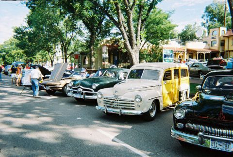 1972 Ford Ranchero - A row of classic cars are parked on a street, with a cream and yellow Ford Woody Wagon in the foreground.