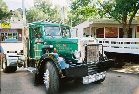 1972 Ford Ranchero - A vintage green semi-truck is parked next to a white trailer at a car show.