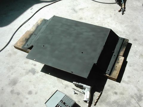 1978 Ford Bronco - Metal skid plate and tools on concrete floor.