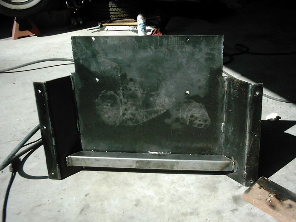 Black metal transfer skid plate with a silver metal bar across the bottom, showing some smudges and weld marks