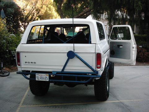 1978 Ford Bronco - Rear view of a white 1978 Ford Bronco a blue roll cage and external spare tire mount.